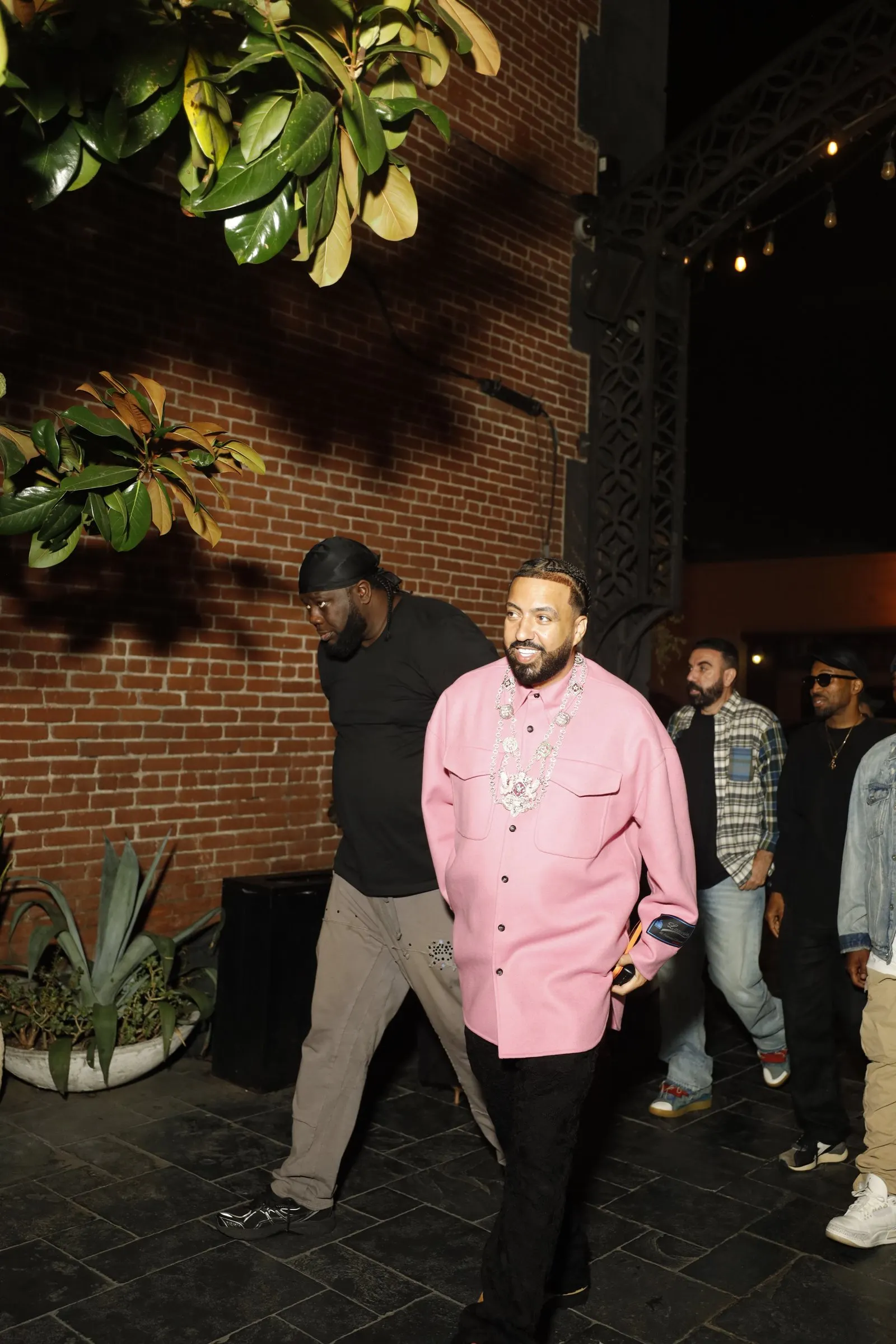 French Montana, wearing a pink embellished shirt, walks into Koza Hollywood with his crew